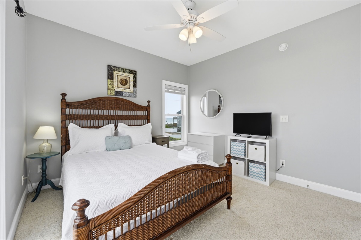 Top floor bedroom with TV, dresser storage, and natural light