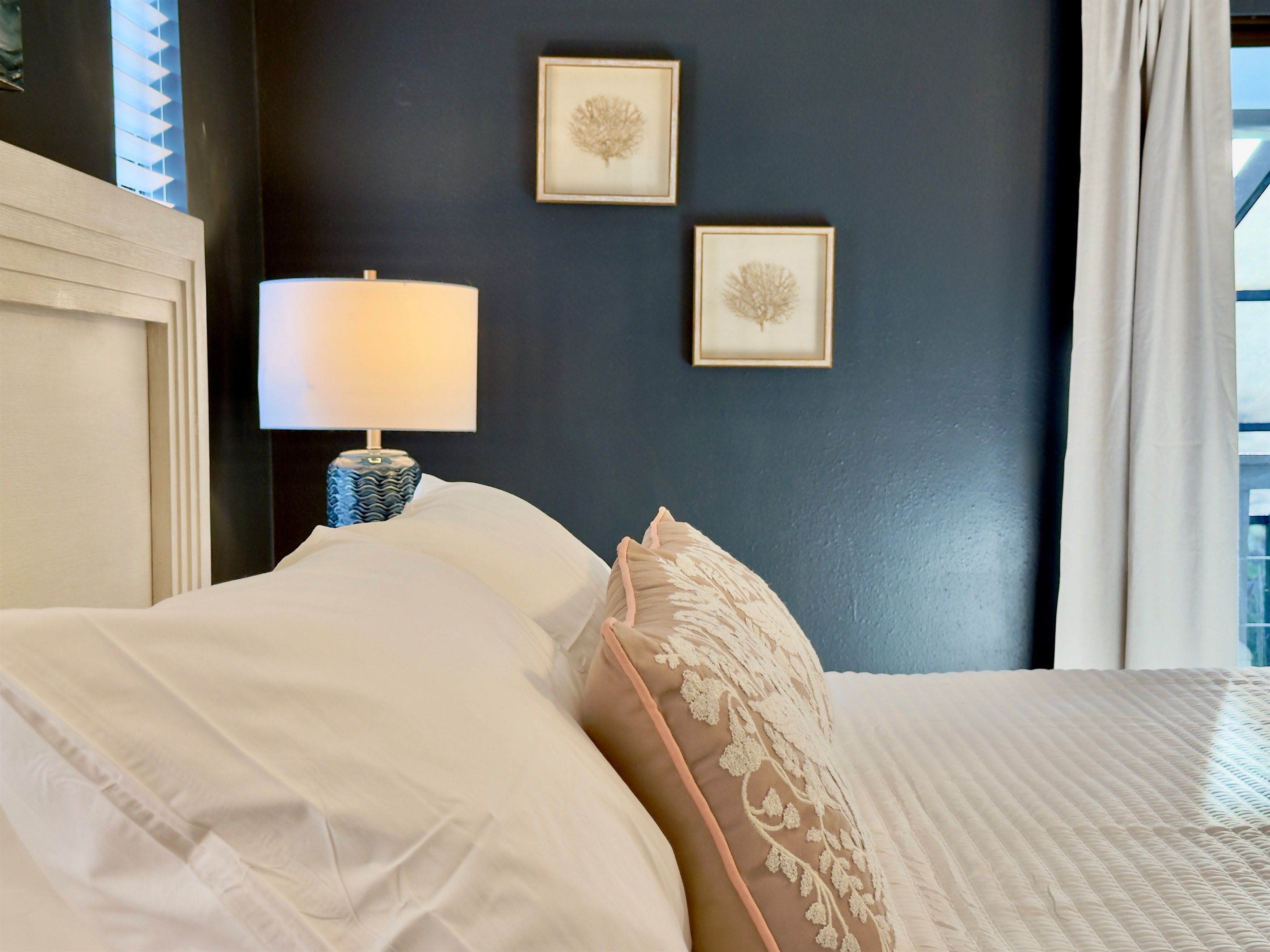 Framed artwork—including a dramatic ocean wave centerpiece—adds a serene coastal vibe that ties beautifully into the overall beachy, modern-chic aesthetic.