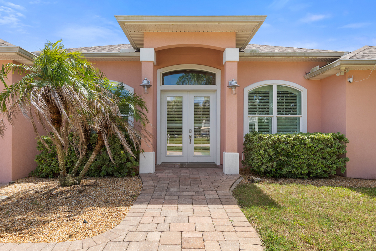 Paver path to arched French doors with lantern lights, a welcoming entry that is easy to find after dark.