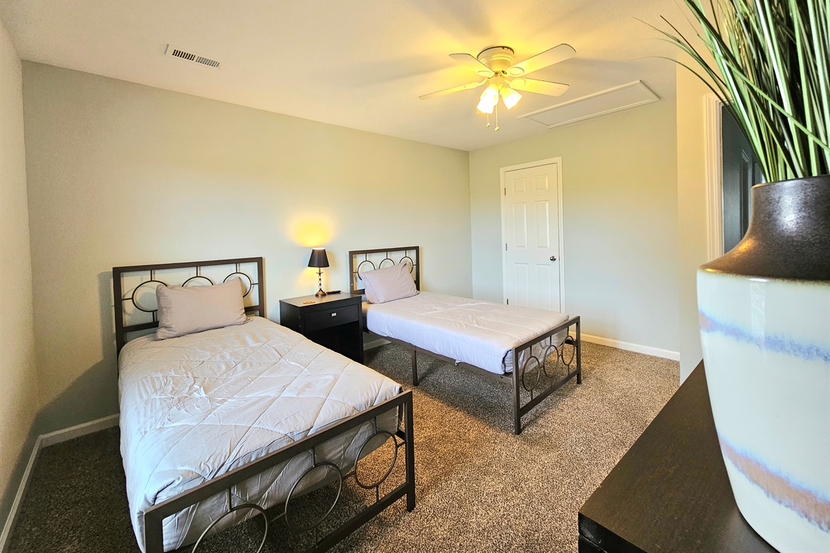 Guest room with two twin beds and large smart TV.