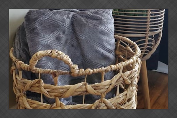 Charming corner setup with a woven basket of cozy throws and a decorative planter—adding warmth and natural texture to the space.