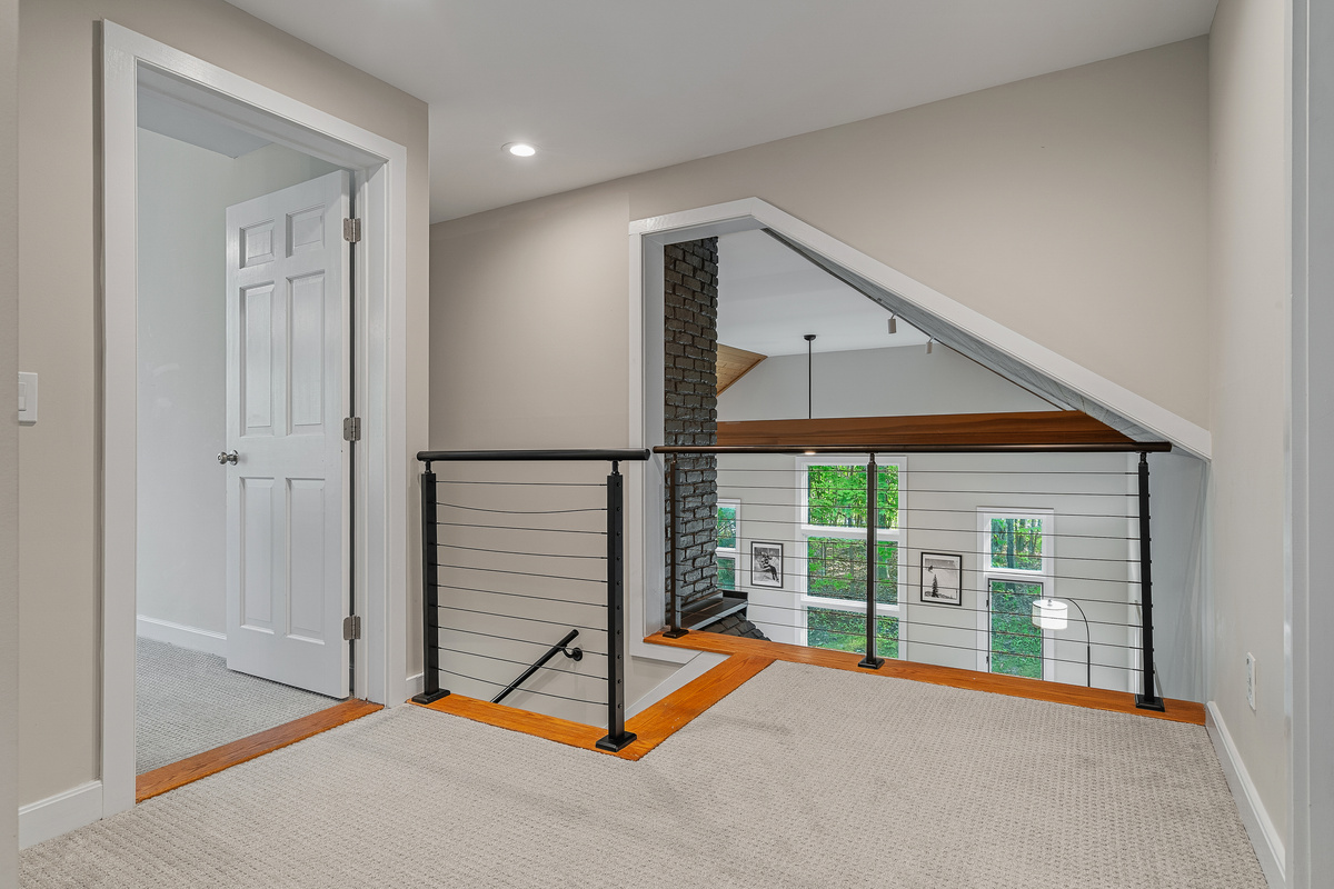Upstairs landing with cable railing overlooking the great room and fireplace