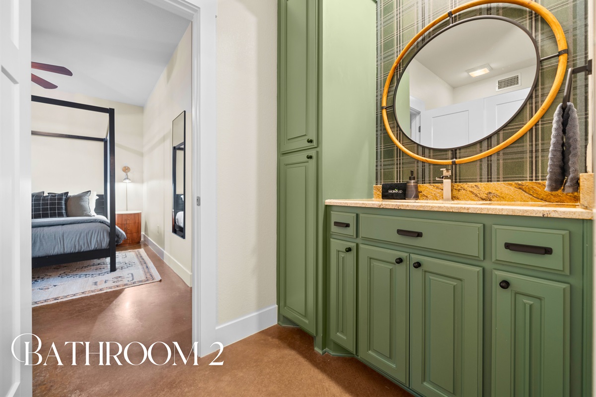 Bathroom two stands out with its striking green cabinetry and round mirror, adding character and charm to the space.