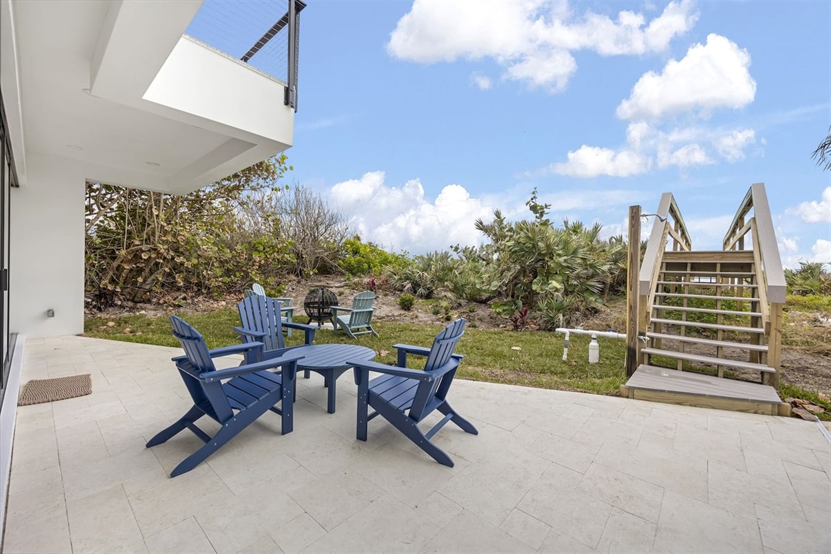 Relax on the terrace with tables and chairs, surrounded by lush greenery, and enjoy the view of a beautiful bridge leading to the ocean, creating the perfect outdoor retreat for relaxation and scenic moments.
