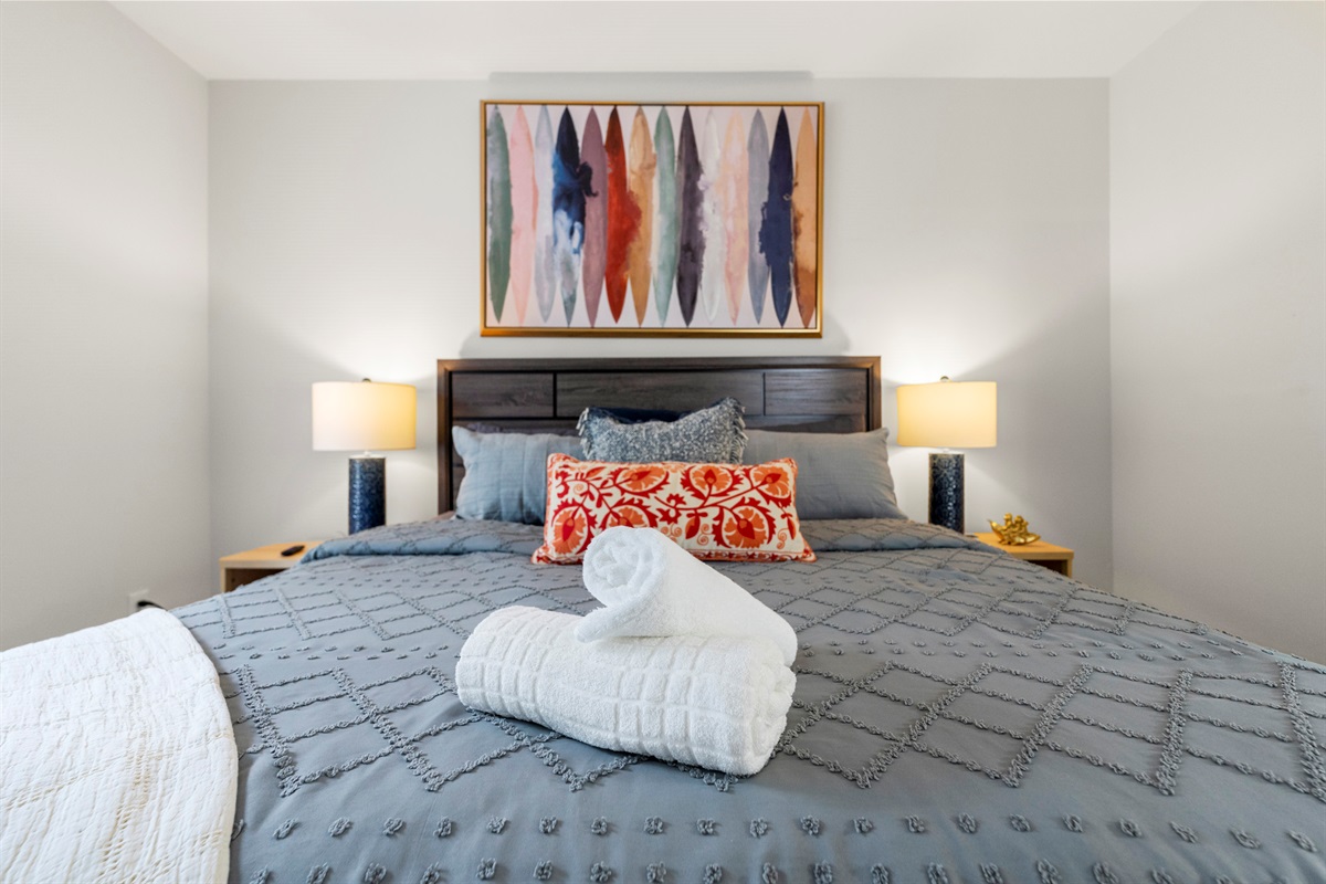 Stylish king bedroom with soft linens and warm, welcoming touches.