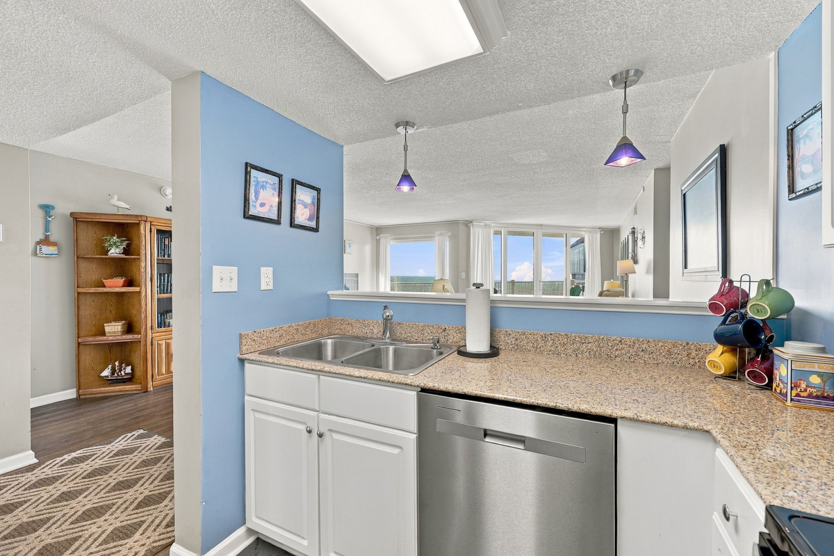 Kitchen view showing light blue accent walls, white cabinetry, granite countertops, and modern stainless steel appliances.
