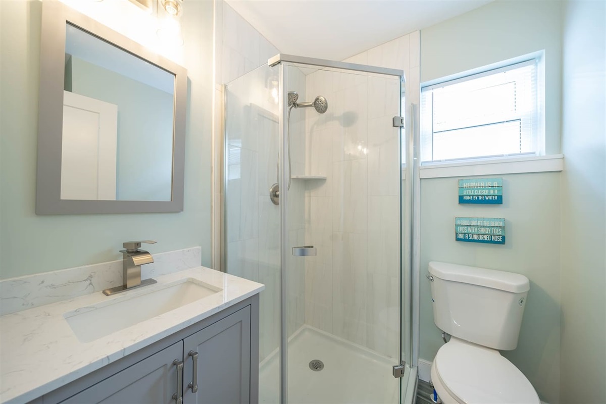 Fresh, modern bathroom with a walk-in glass shower, bright vanity, and clean finishes. Natural light and simple coastal styling create a comfortable space for refreshing showers and an easy start or end to the day.