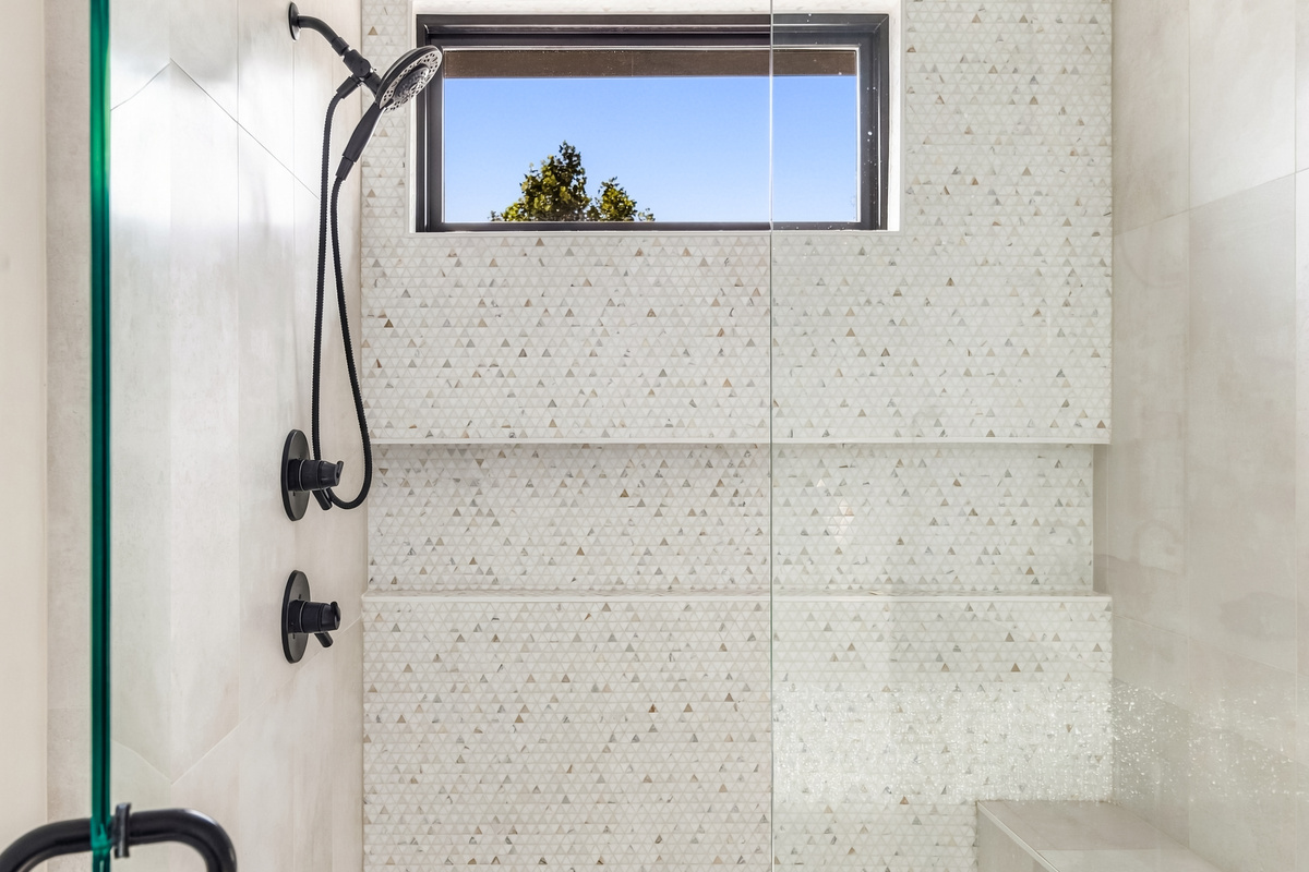 Speckled terrazzo-tile shower with a skylight window for natural light.