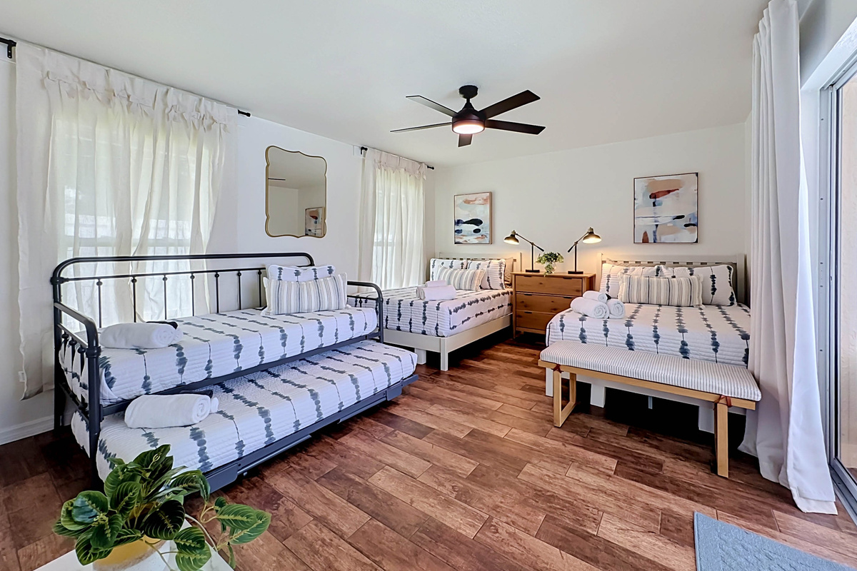 A bright bedroom with 2 full beds and a daybed with a trundle, and direct sliding-door access to the pool — perfect for relaxing and recharging.