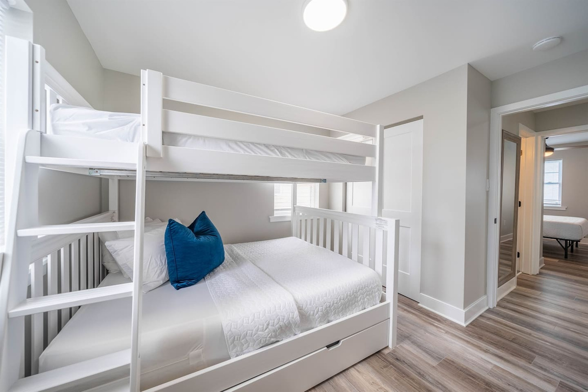 Bright bunk room designed for comfort and flexibility, featuring sturdy twin bunks with clean white finishes and fresh bedding. A great option for kids or extra guests, offering an easy, functional sleeping space with nearby bedroom access.