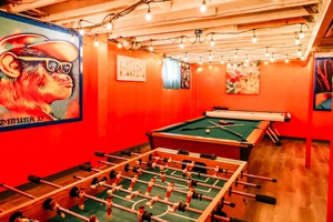 A vibrant red wall sets the stage for endless fun with a classic pool table and an engaging foosball table side by side.