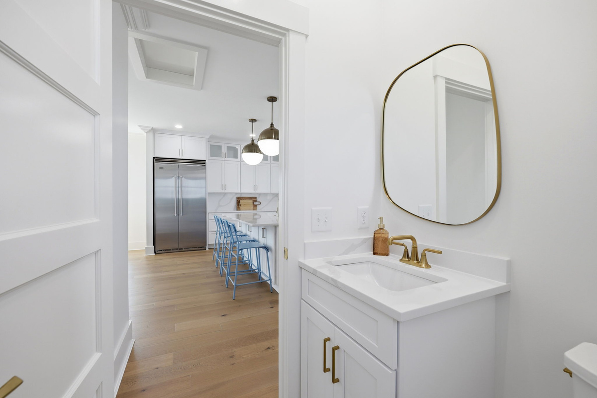 Compact powder room with modern white vanity, gold fixtures, and a minimalist mirror for a clean coastal aesthetic