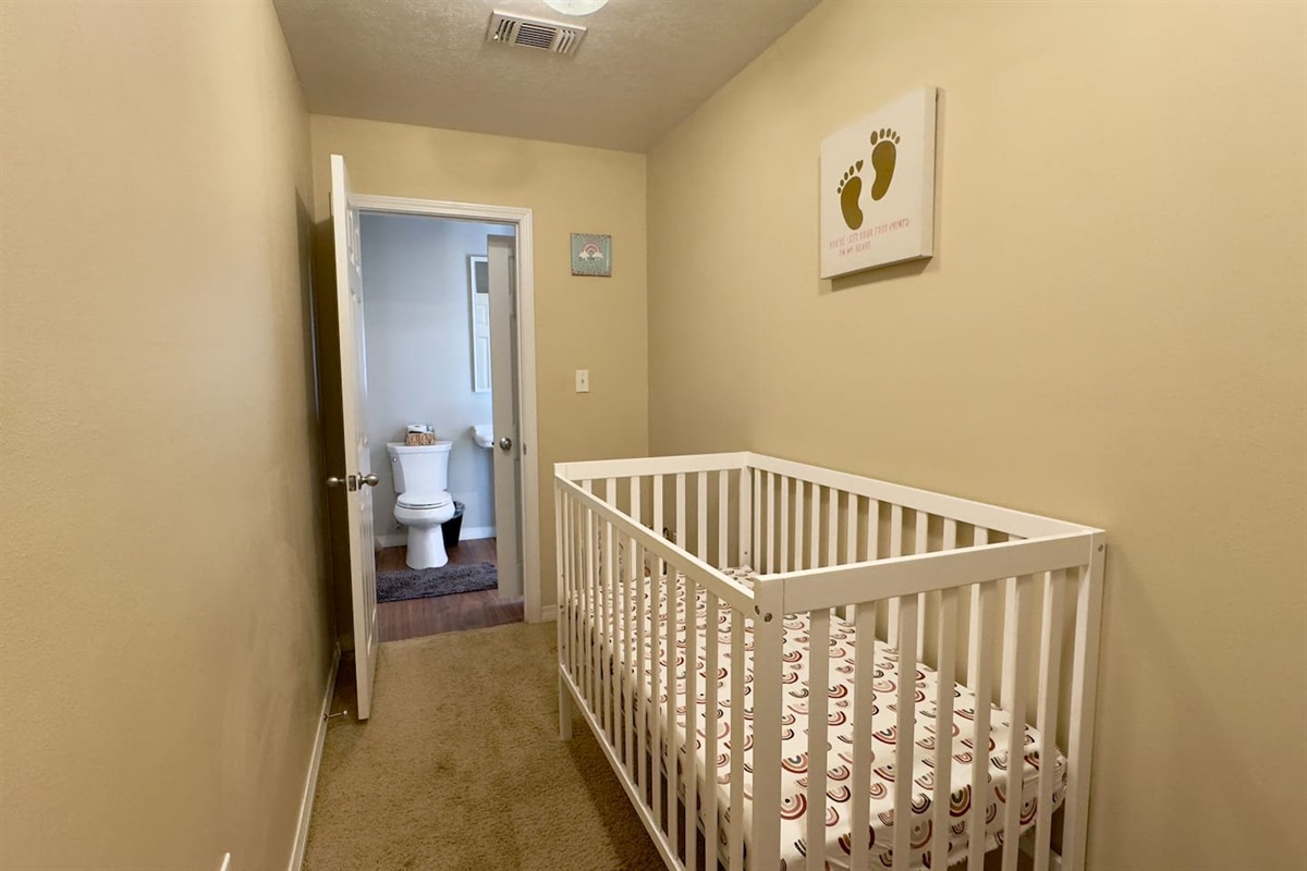 An open doorway leads directly to a bathroom with sink, toilet, and mirror, offering convenience for parents.
