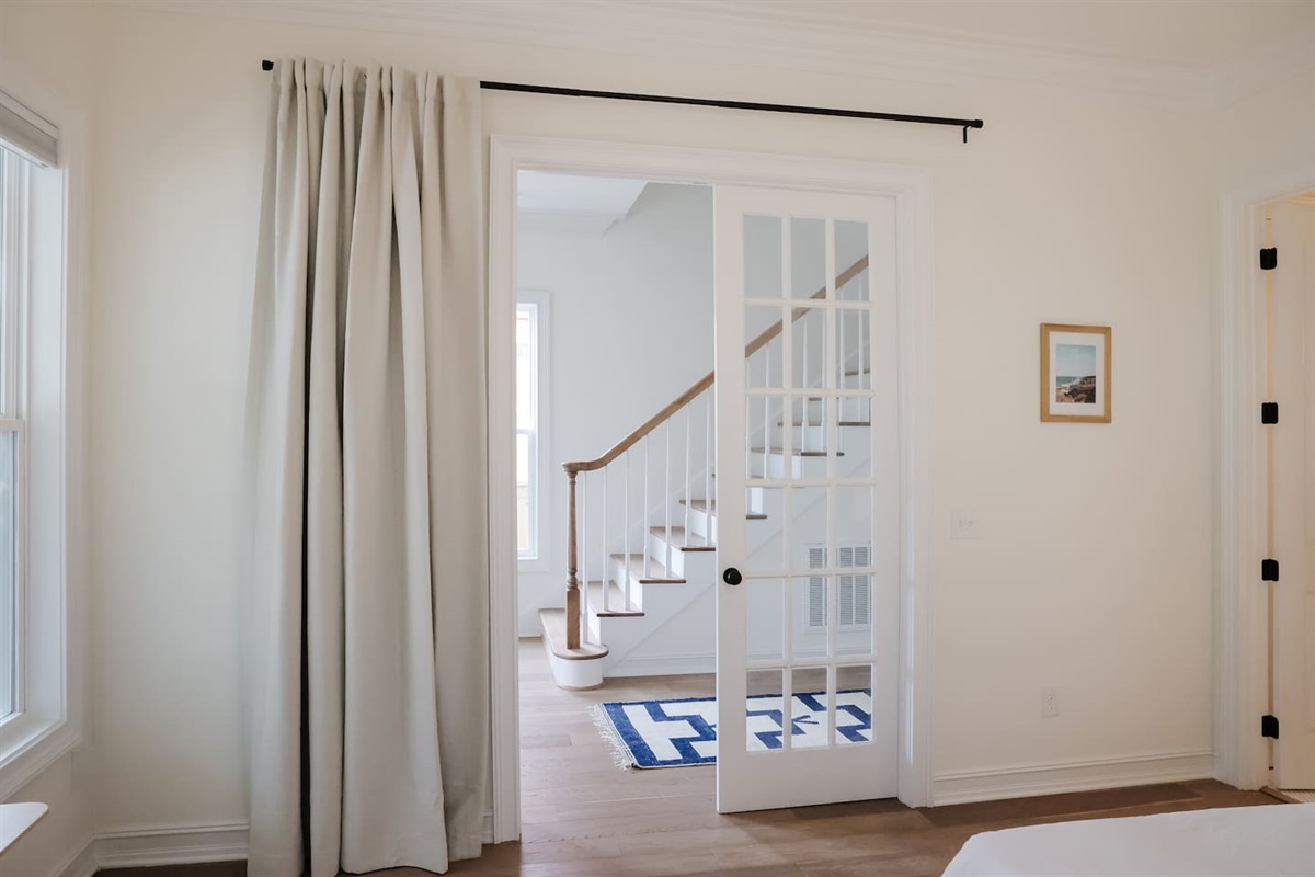 The downstairs bedroom is off of the foyer hallway with glass french doors. Thick blackout curtains provide privacy to room guests.