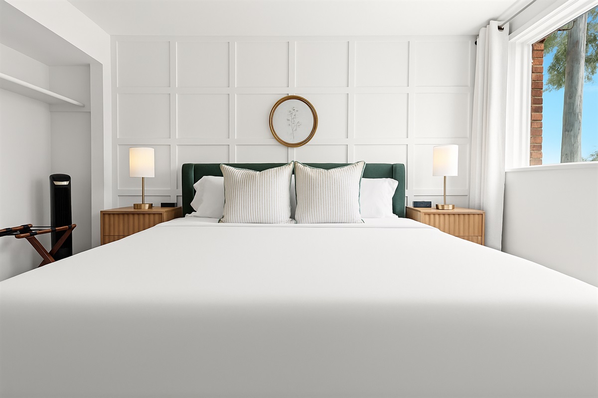 This cozy king suite offers soft linens, blackout curtains, and a touch of elegance with a decorative wall treatment.