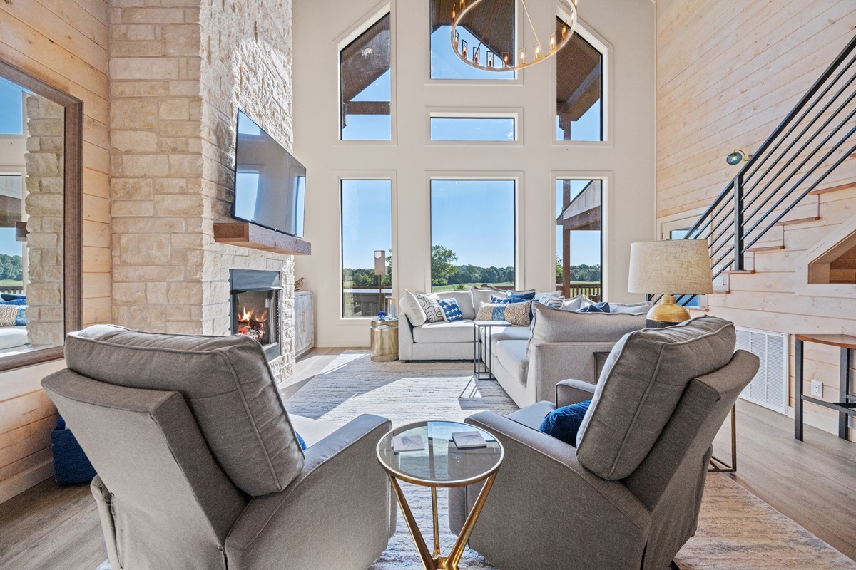 Comfortable seating area by the fireplace with beautiful floor-to-ceiling windows.