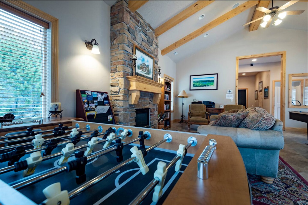 A vibrant entertainment space featuring foosball, comfortable seating, and a grand fireplace—designed for both lively competition and relaxed socializing.