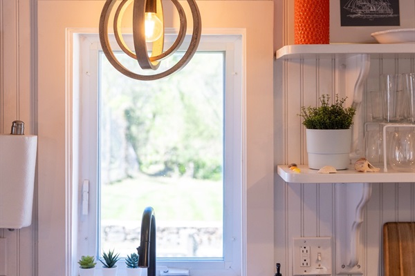 Farmhouse sink at the heart of the kitchen, with open shelving stocked with everything you may need for a comfortable stay.
