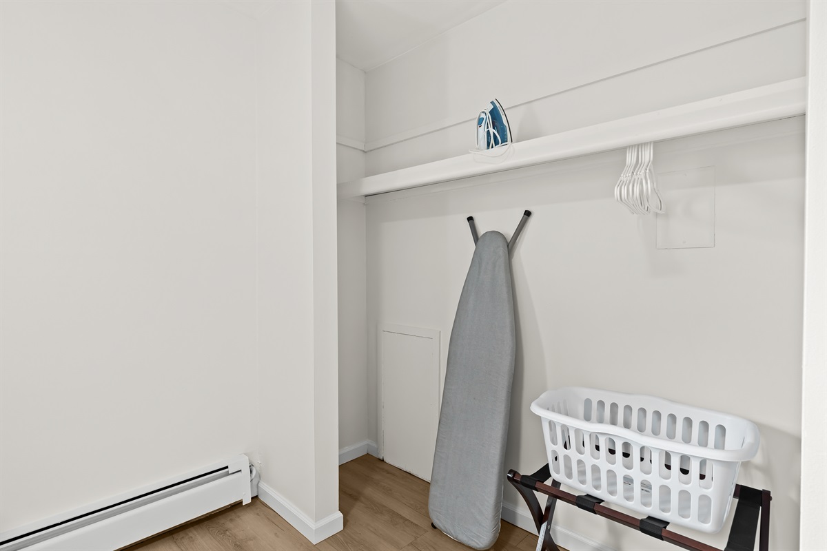 Closet space equipped with ironing essentials and extra storage for your convenience.
