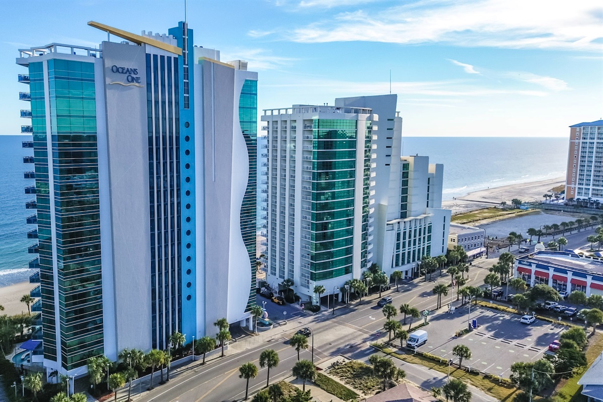 - Oceanfront resort building exterior featuring tall windows and unique blue trim   - Modern architecture highlights Myrtle Beach skyline with contemporary coastal look   - Vacation stay offer