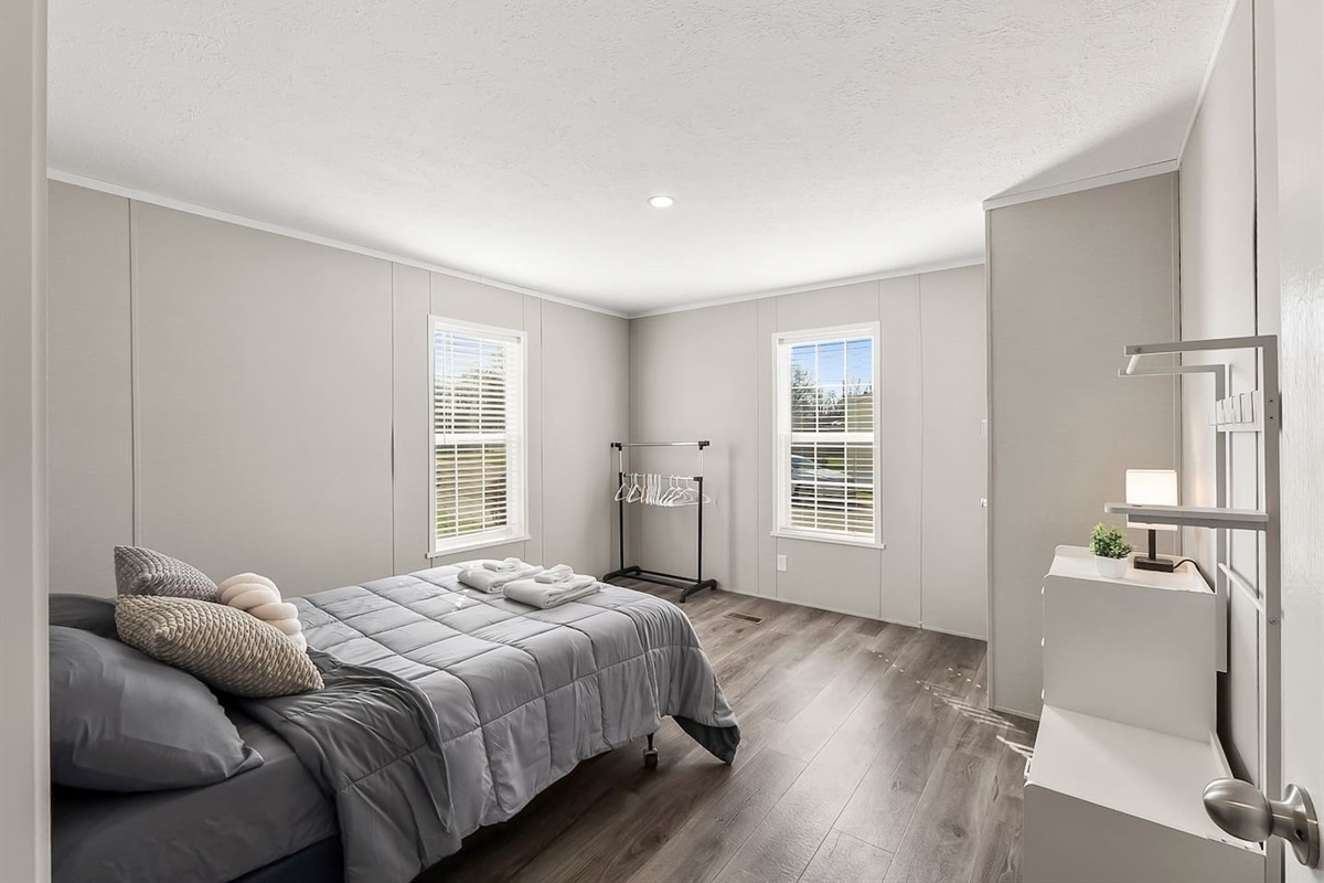 Bright and airy bedroom with a queen bed, large windows, and natural light creating a warm, inviting atmosphere.