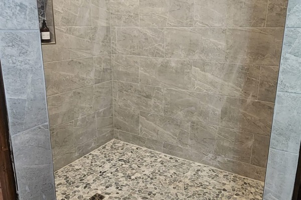 Spacious walk-in shower with full tile surround.
