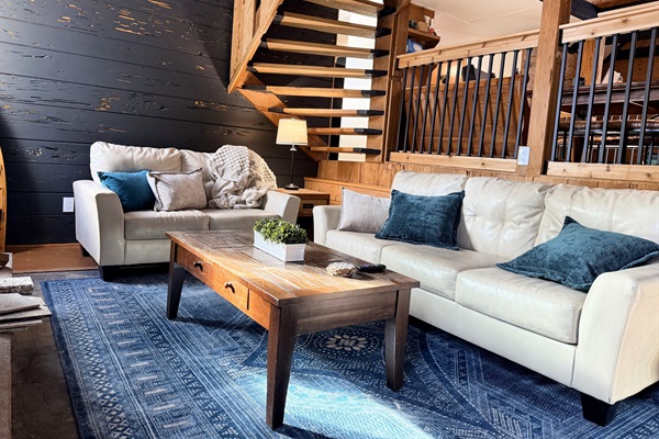 Unwind in your cozy living room with plush seating next to a crackling fire in the stone fireplace. Soft throws and a rustic wood coffee table—perfect for game nights, reading, or relaxing by the warmth of the cabin charm.