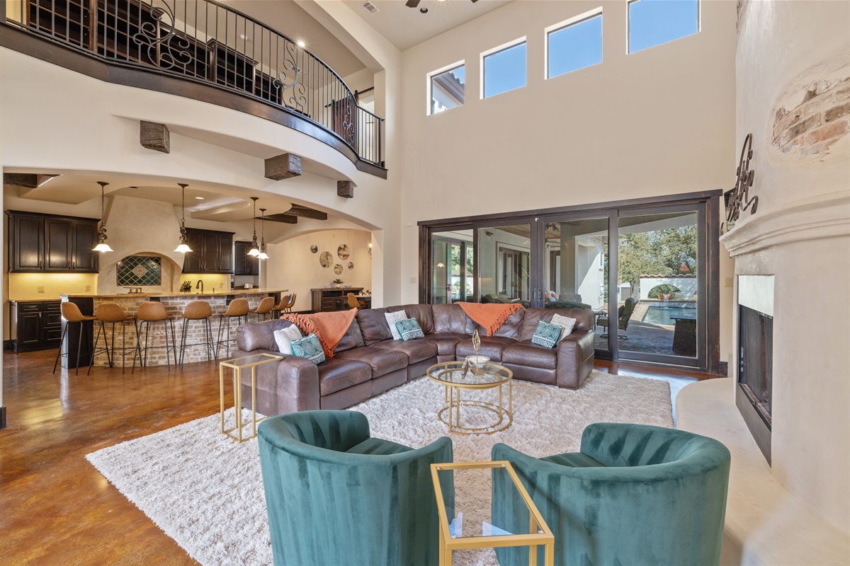 "Welcome to the heart of the house! This spacious living room boasts over 20-foot ceilings, abundant seating, a cozy fireplace, and a smart TV—all with stunning views of the resort-style pool.