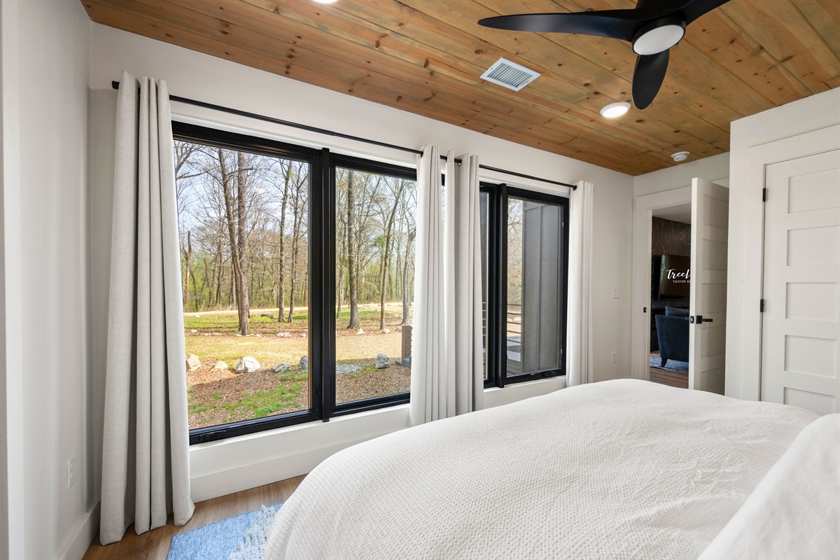 Large windows in the bedroom bring in plenty of natural light and views of the outdoors, creating a peaceful and airy place to wake up.
