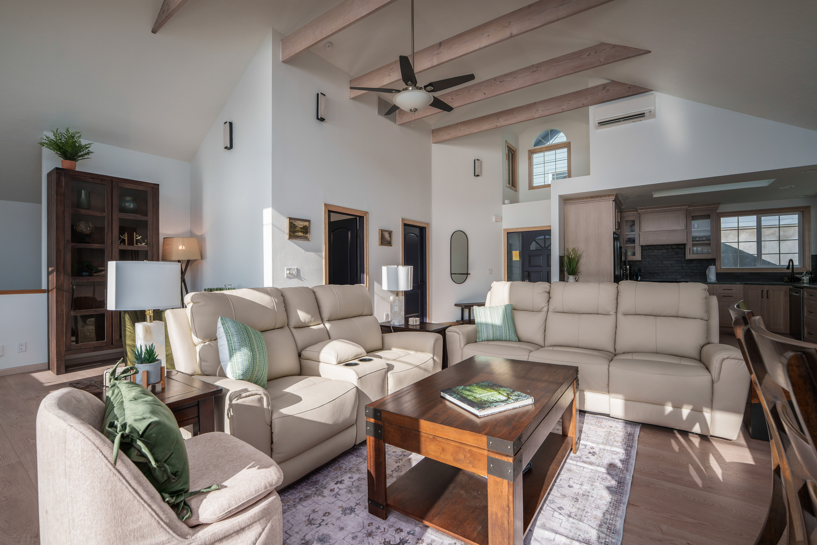 Bright, inviting living room with vaulted ceilings, exposed wood beams, comfortable seating, and plenty of space for the whole group to relax together. Coffee table converts into a laptop-friendly working station.