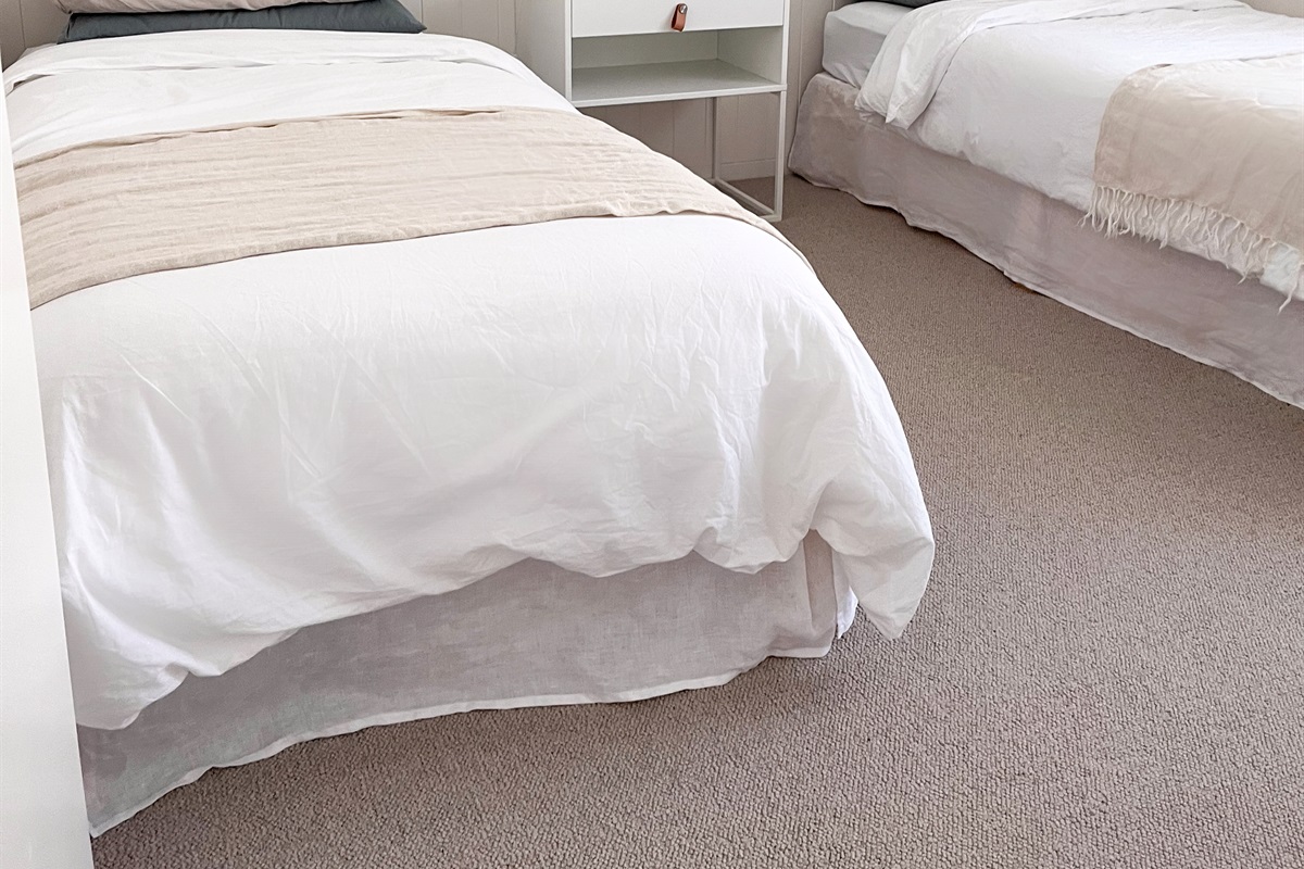 This bedroom adds another comfortable sleep space, with layered bedding, bedside lighting and a simple uncluttered layout.