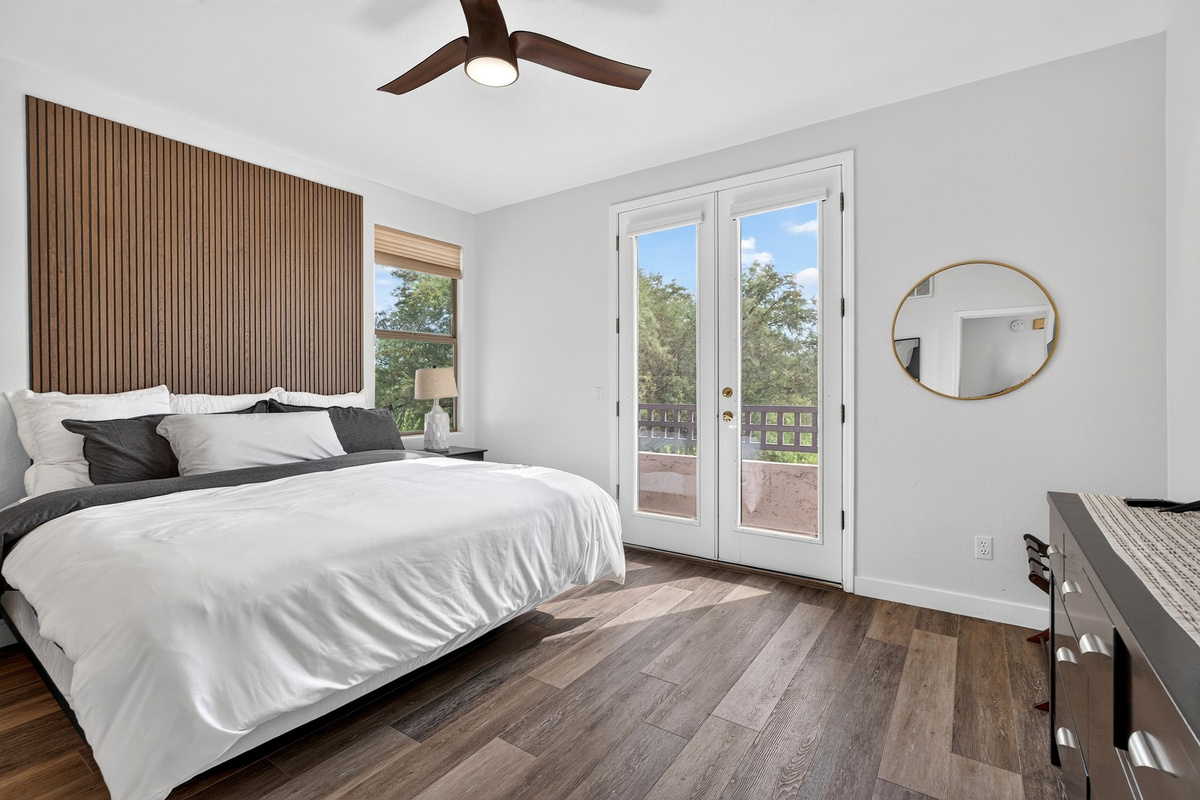 King bedroom with soft layered bedding, bedside lighting, and private balcony access for a comfortable stay.
