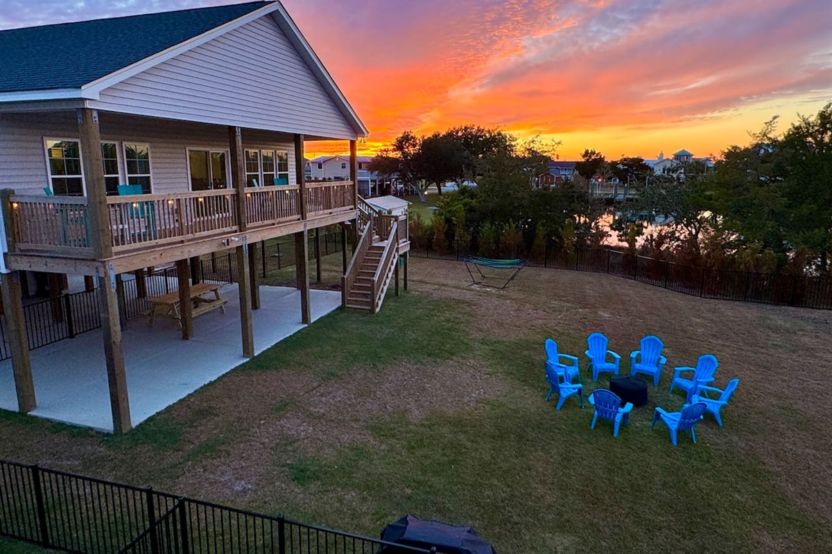 Private backyard dock with boat lift and fillet table, fenced-in backyard, fire pit with Adirondack chairs, hammocks, propane grill, picnic table, outdoor shower, expansive waterfront back deck, neighborhood boat ramp and dock