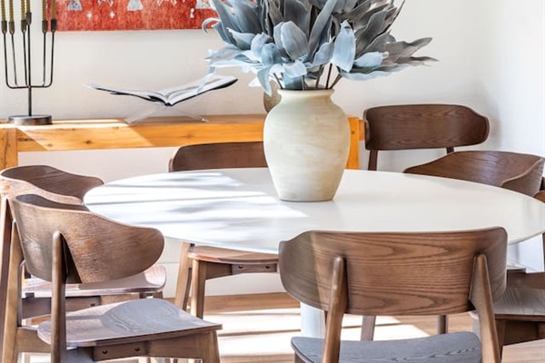 Dining room detail featuring curated décor, warm wood tones, and statement art. Thoughtful styling and natural light create an inviting atmosphere for shared meals and relaxed gatherings for up to 8.