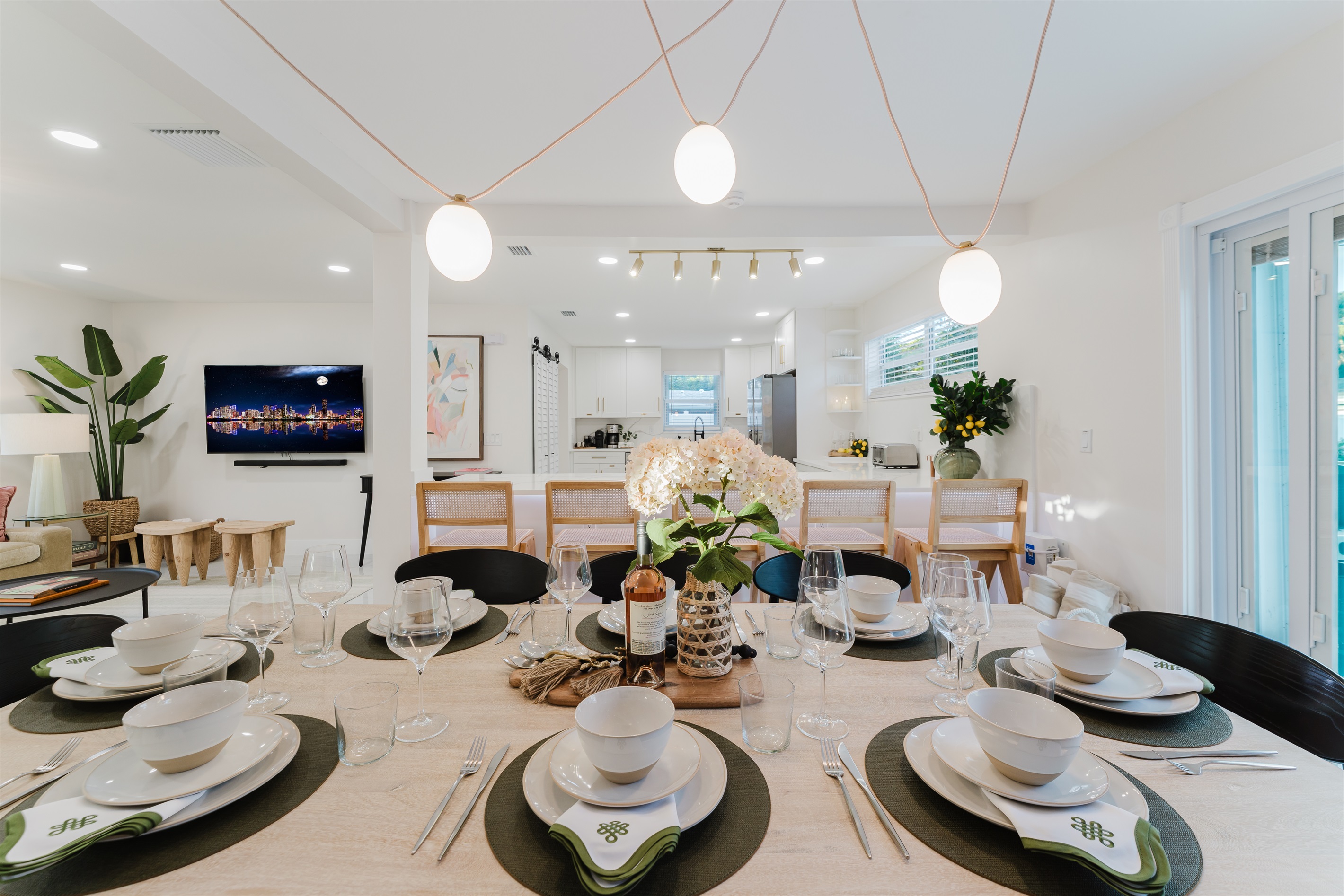 Designer dining room featuring a Gwyneth Paltrow GOOP statement light, custom wallpaper, and seating for 12. Backlit counter seating and seamless access to the patio and backyard make this space ideal for family meals and entertaining.