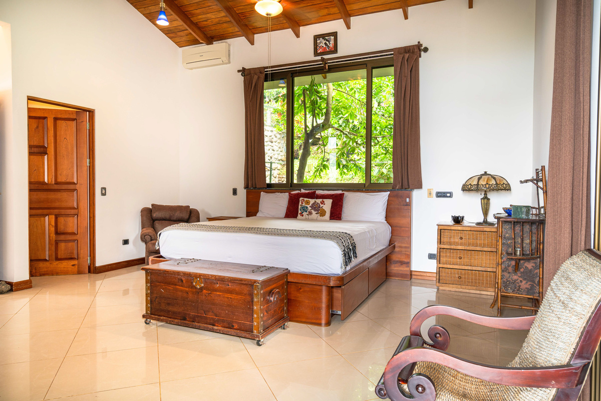 King bedroom suite with warm wood details and lush jungle views