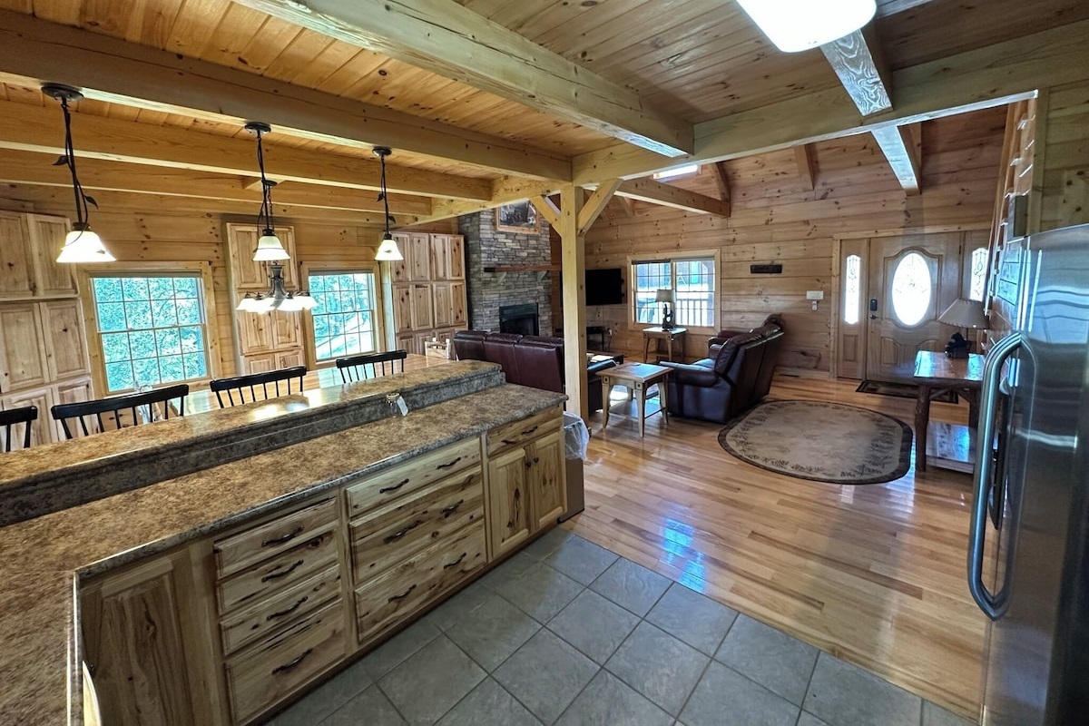 The kitchen has a large L-shaped countertop with lots of seating space for high-back chairs, lots of cabinet space, and a huge amount of cabinet storage space in the back behind the dining table against the back wall. 