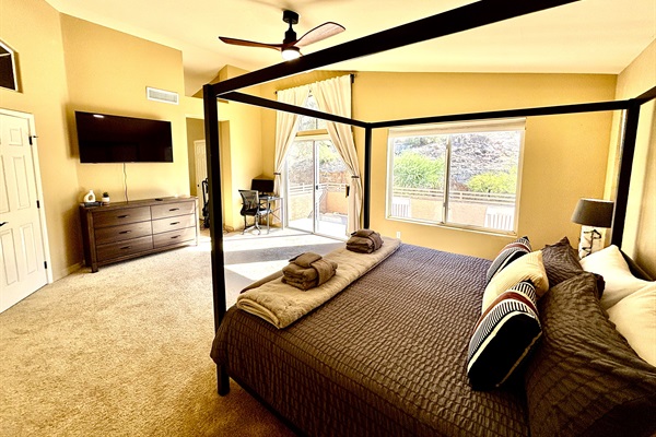 Primary suite with king bed, 55' smart tv, blackout blinds, ceiling fan, remote workstation, walk in closet, ensuite bathroom and private deck