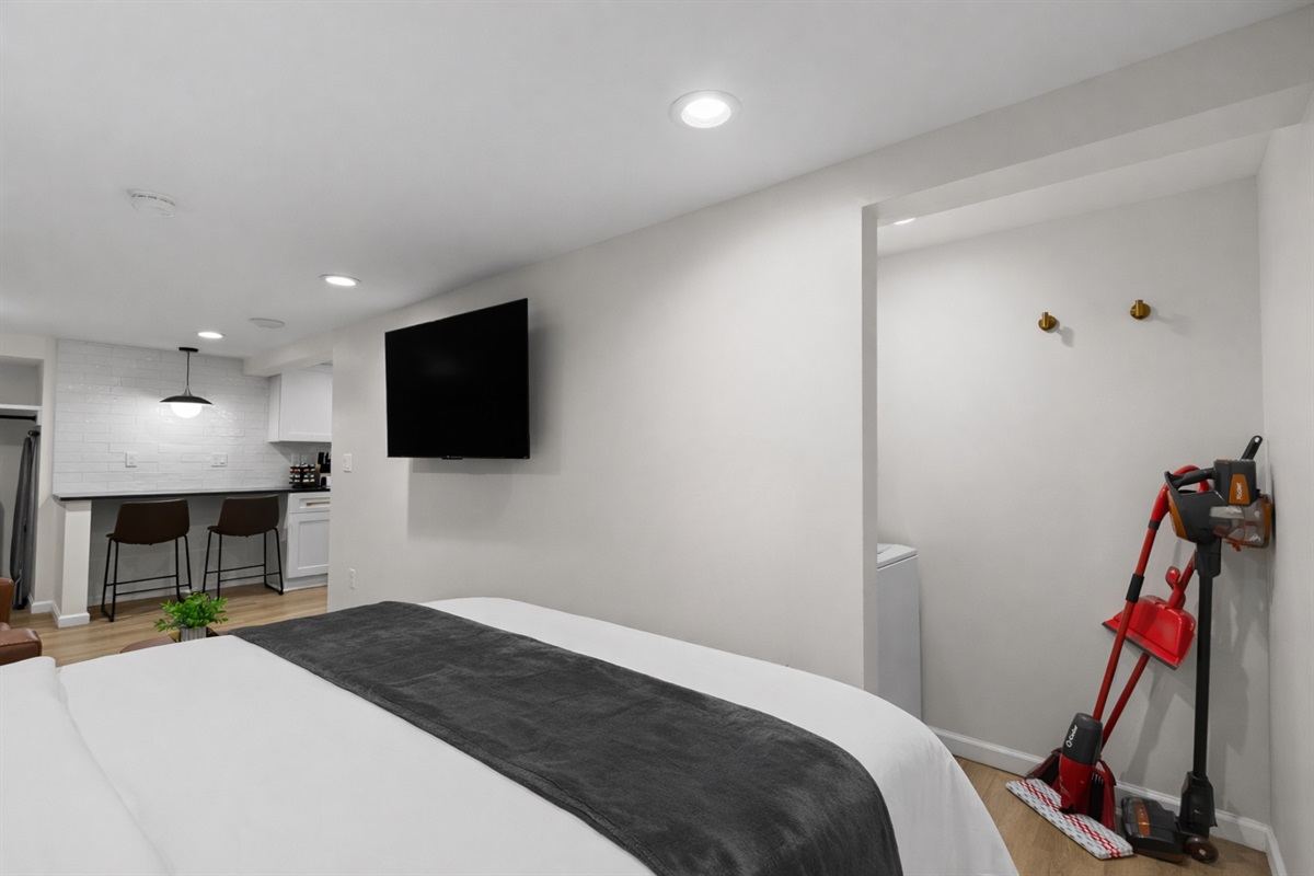 Open, airy studio layout with a plush bed, wall-mounted TV, and convenient storage area—designed for comfort, functionality, and an easy, relaxed stay.