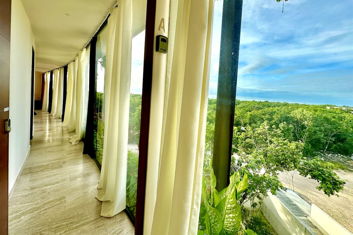 A circular hallway has floor to ceiling glass walls that take in the view.