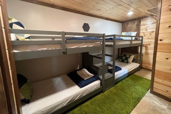 Bunk room with four beds and private bathroom—comfortable for adults or kids alike.