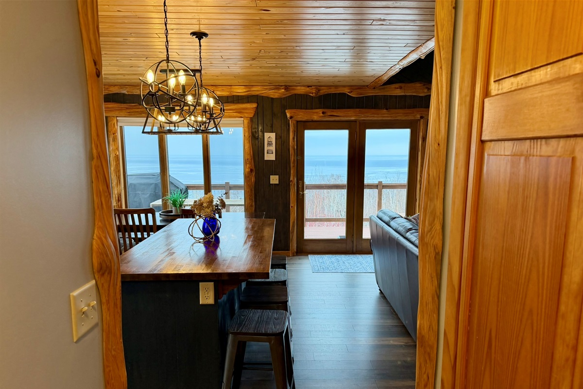Stepping into the main room Lake Superior view hits you with open living room + kitchen with the island just coming into view. Bright windows, and a welcoming layout made for relaxing together.