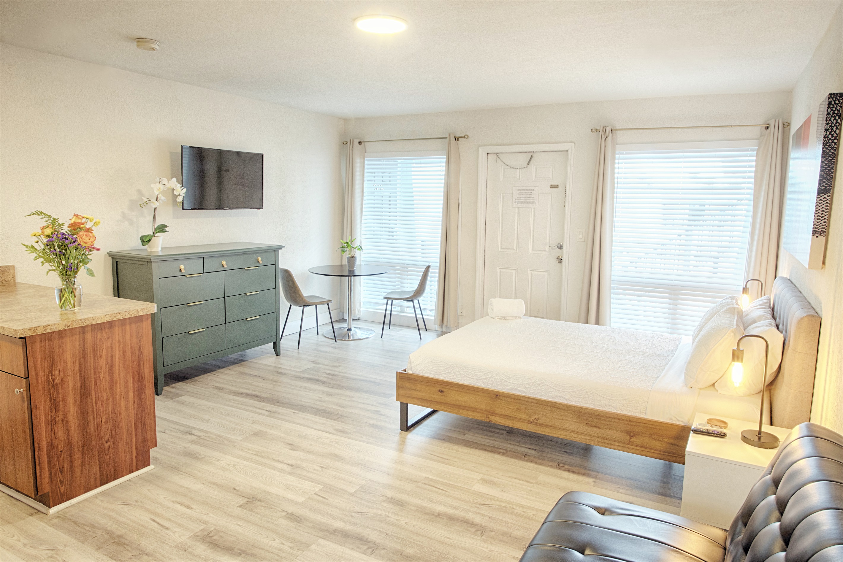 Multiple seating options show futon, kitchen counter stools and dining table by large windows.