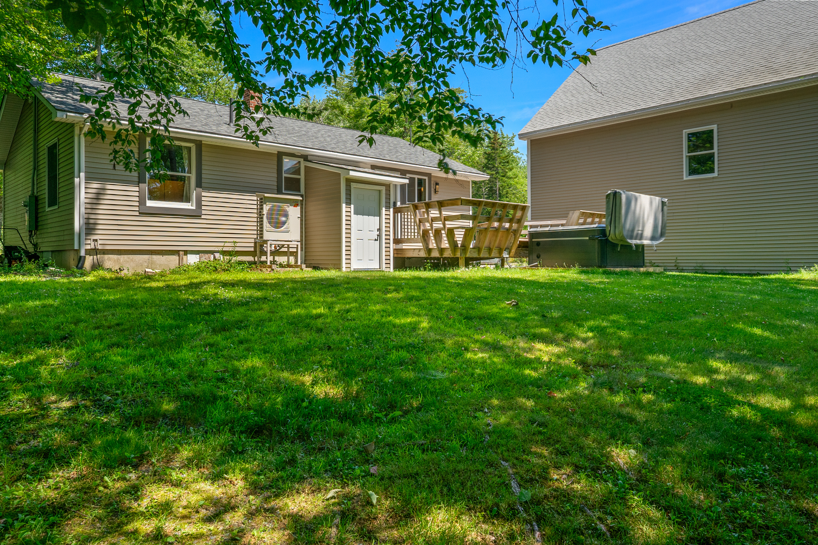Relax in the spacious backyard featuring an overhead dog tether run for your pets. View shows the outdoor deck with integrated bench seating, the 6-person hot tub, and the mini-split heat pump providing efficient cooling to the main floor.