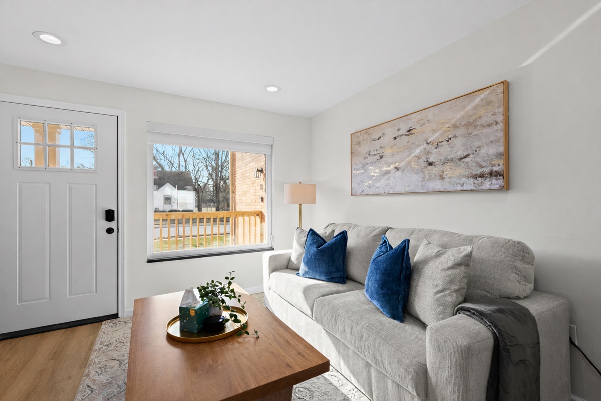 Bright, comfortable living room with plush sofa, natural light, and tasteful décor—perfect for relaxing or enjoying a cozy night in.