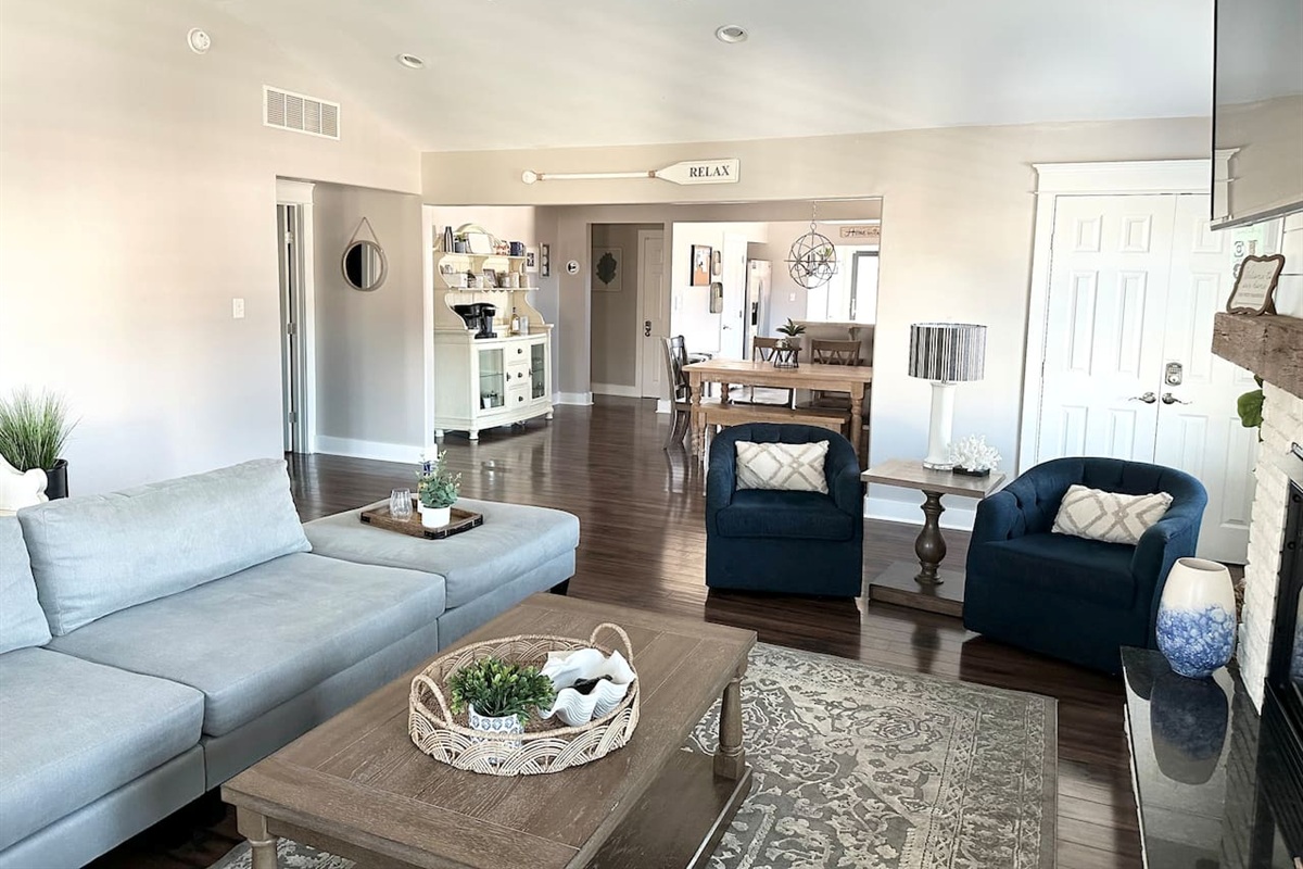 Experience the seamless flow of our open-concept living space, where the cozy seating area leads right into a charming dining nook. With neutral tones and coastal accents like the "RELAX" oar, it’s a tranquil environment designed for easy vacation living.
