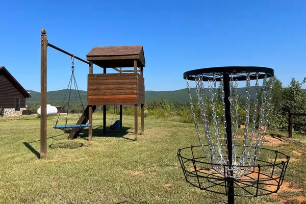 Disc golf course set beside open views and outdoor play area / playground in the backyard.