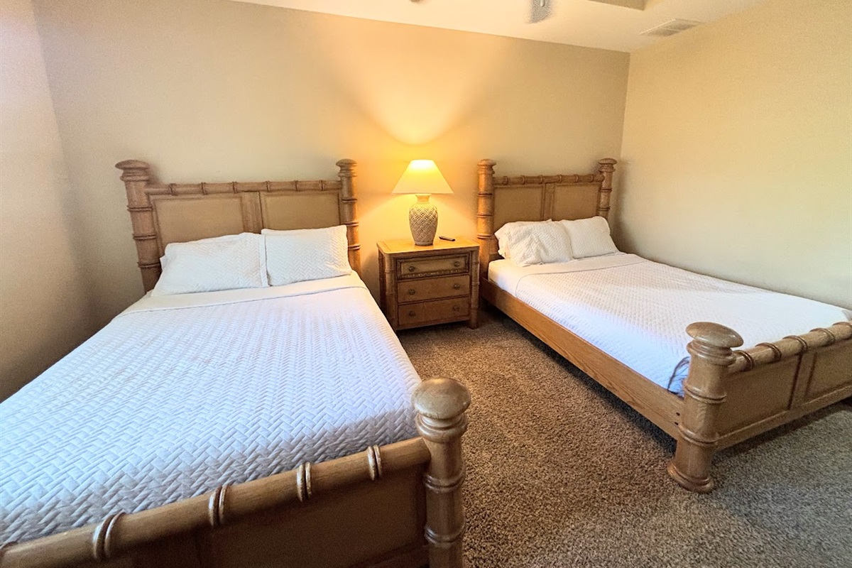 Inviting bedroom with two comfortable beds, matching nightstand, and warm lighting — perfect for guests or family stays.