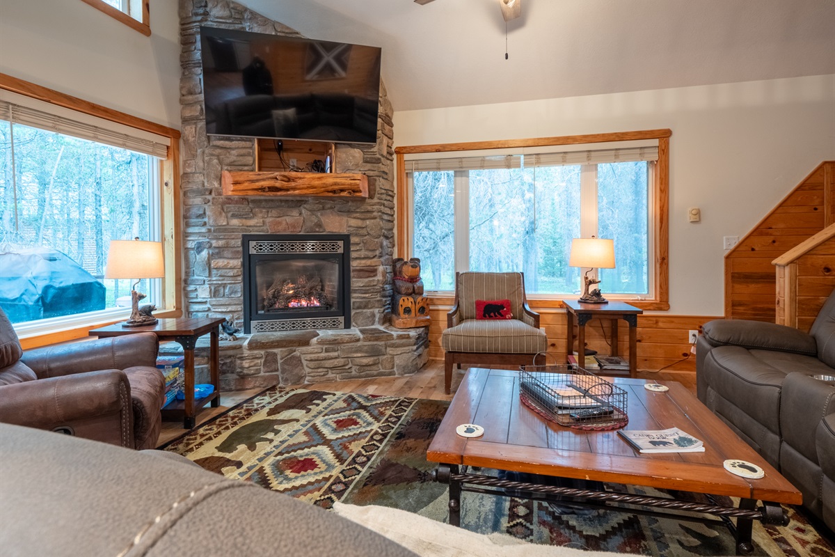 Warmth and a restful fireplace with a view of the trees and stairs to the loft/bedroom, and bedroom 3