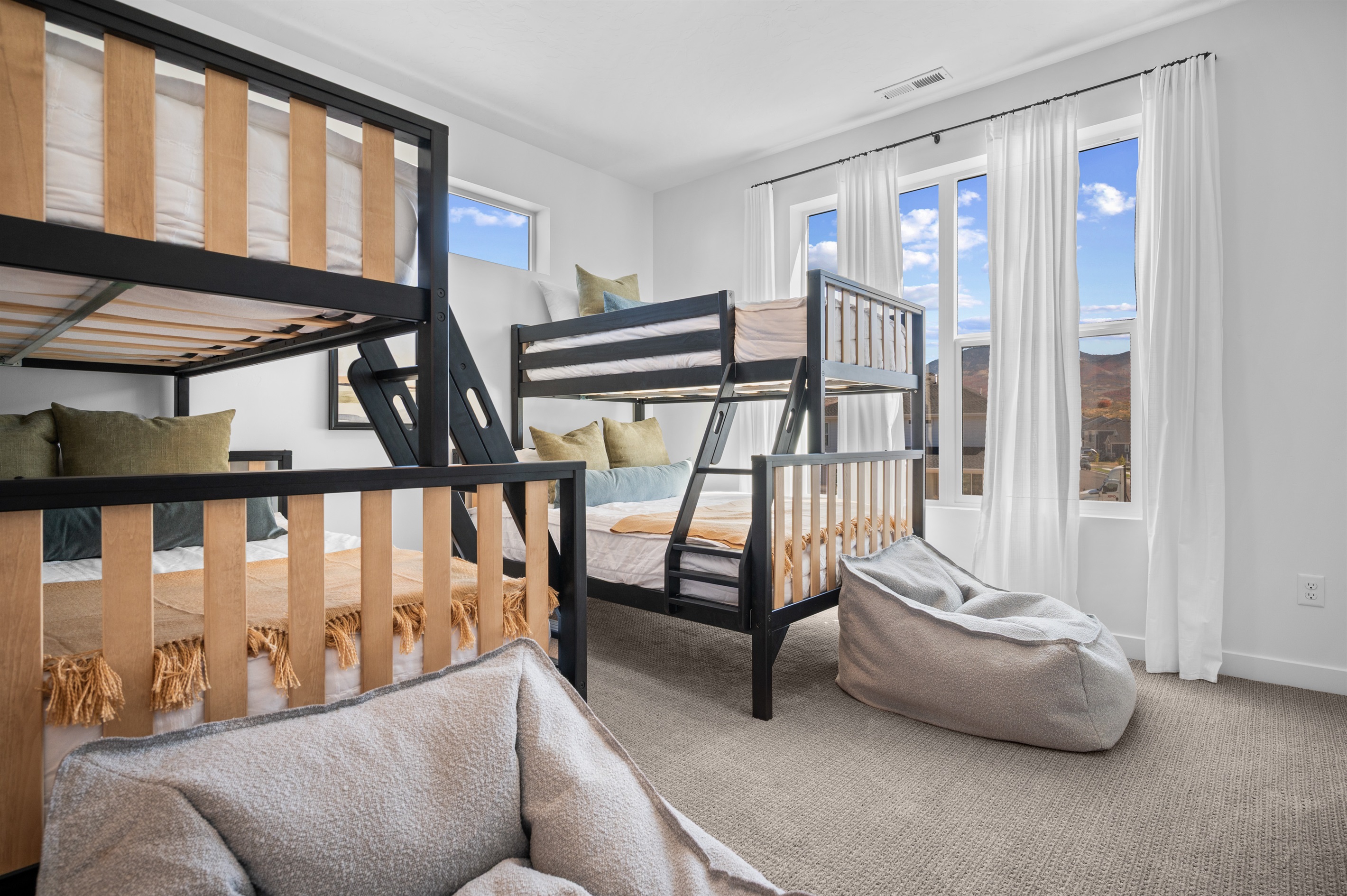 Bright and inviting bunk room featuring cozy beds and mountain views.
